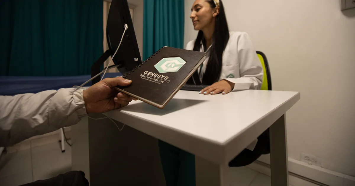 Paciente entrega su cuaderno de documentos a la médica en consulta en Genesys Laboral Medicine