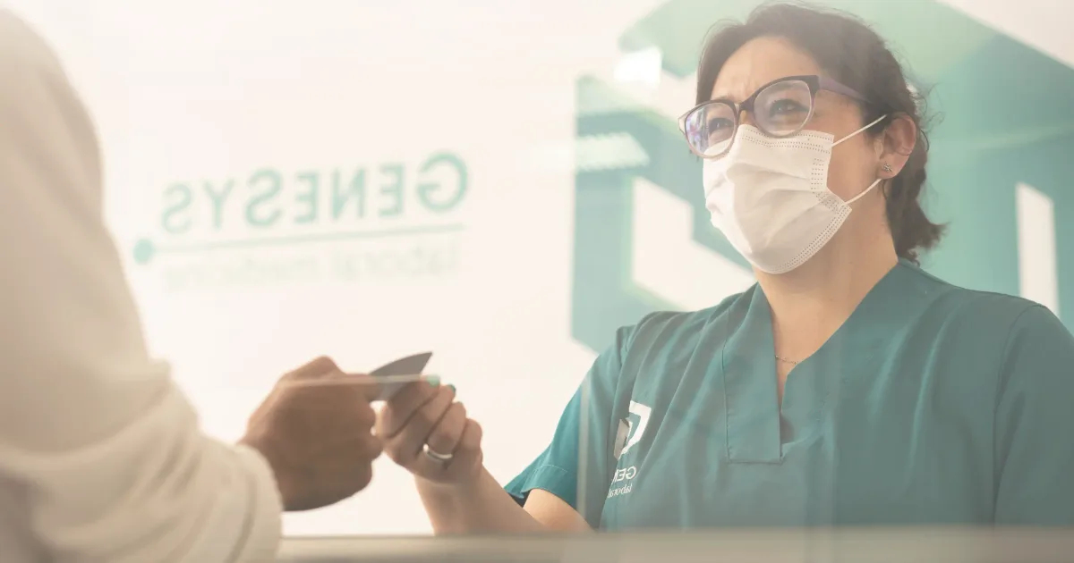 Recepcionista de Genesys Laboral Medicine entregando un documento a un paciente